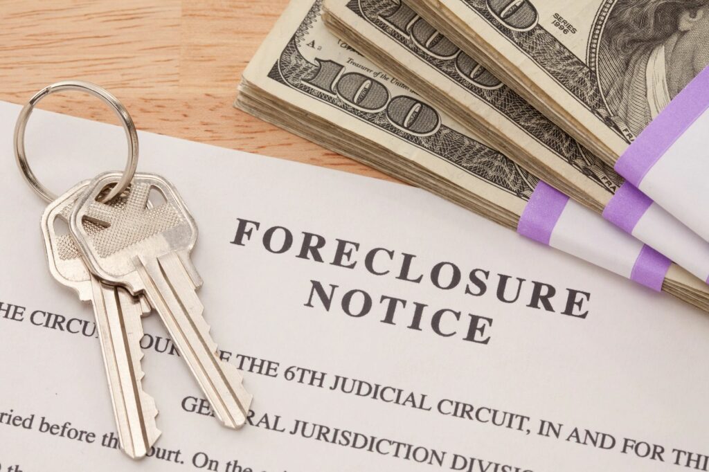 Keys and a stack of money on top of a foreclosure notice.