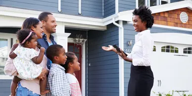 Realtor giving tour outside a home to a family